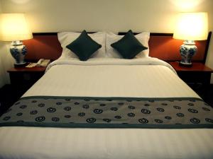 a bedroom with a large bed with two lamps at Hotel Royal in Singapore