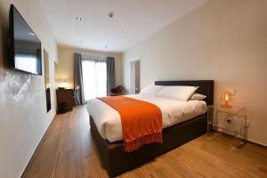 a bedroom with a large bed with an orange blanket at Quaint Boutique Hotel Sannat in Sannat