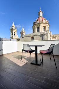 a table and two chairs on the roof of a building at Quaint Boutique Hotel Sannat in Sannat