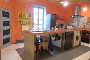 een keuken met oranje muren en een aanrecht met een wastafel bij gîte de la Domergue in Mas-Saintes-Puelles