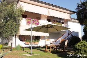 a table with an umbrella in front of a house at Antico Borgo in San Daniele del Friuli