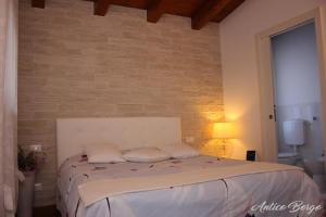 1 dormitorio con 1 cama con pared de ladrillo en Antico Borgo, en San Daniele del Friuli