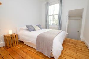 a white bedroom with a bed and a window at Central Garden Apartment in Brighton & Hove