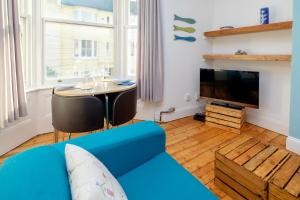a living room with a blue couch and a tv at Central Garden Apartment in Brighton & Hove