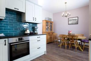 a kitchen with white cabinets and a dining room with a table at Driftwood Cottage in Seahouses