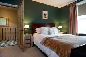 a bedroom with a large bed with green walls at Driftwood Cottage in Seahouses