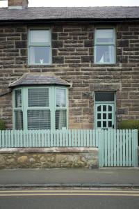 a white picket fence in front of a brick house at Driftwood Cottage in Seahouses
