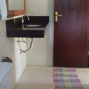 a bathroom with a sink and a mirror and a door at Pousada Recanto do Sossego- Serra da Canastra in Vargem Bonita