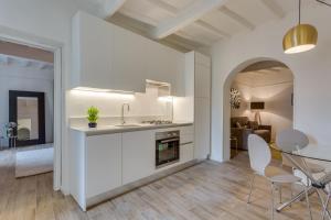 フィレンツェにあるApartments Florence - Chiara Stylishの白いキャビネット、テーブルと椅子付きのキッチンが備わります。