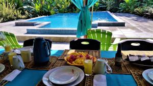 a table with a bowl of food and a swimming pool at Tropical Paradise Bungalows in Pital