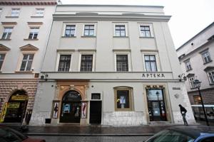 a white building on a street with cars parked in front at Main Market Square Apartments in Krakow