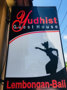 a sign on a building with a woman in a house at Yudhist Guest House in Nusa Lembongan