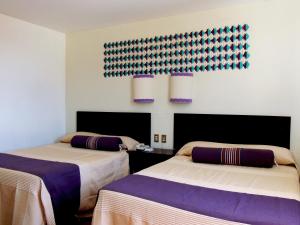 two beds in a room with purple and white at Parador del Dominico in Oaxaca City