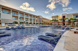 a swimming pool at a resort with chairs and tables at Royalton Hideaway Punta Cana, An Autograph Collection All-Inclusive Resort & Casino - Adults Only in Punta Cana +91 photos