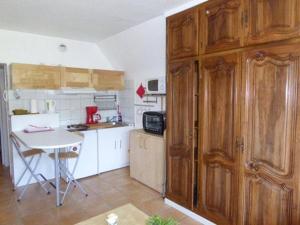 una cocina con armarios de madera y una mesa. en la Charbonnière, en Bellefosse