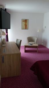 a room with a tv and a chair and a table at Les Balcons Du Velay in Monistrol-sur-Loire