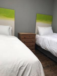 a bedroom with two beds and a dresser between them at Boutique Apartment Ballina Town Centre in Ballina