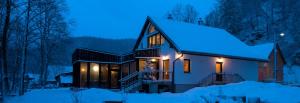 dom pokryty śniegiem w nocy w obiekcie Wellness privát Štyri Lipy w mieście Liptovské Revúce
