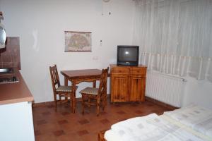 Zimmer mit einem Tisch und einem TV auf einem Holzschrank in der Unterkunft Emanapartmanok Sárvár in Sárvár