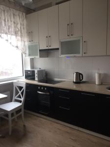 a kitchen with white cabinets and a table and a chair at Morskaya zhemchuzhina na Marselskoy in Kryzhanivka