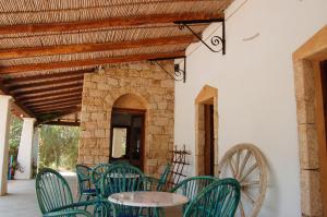 un patio con sedie verdi, tavolo e ruota di Principessa de Navarra a Santa Maria Navarrese