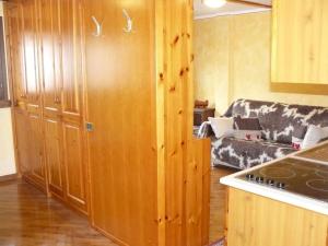 a kitchen with wooden cabinets and a living room with a couch at Charme a Cervinia Downtown Ski in-Ski out in Breuil-Cervinia