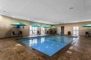 a large swimming pool with umbrellas in a building at Comfort Suites - University in Lubbock