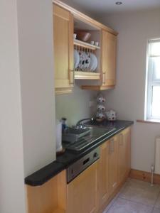 uma cozinha com armários de madeira, um lavatório e uma janela em Earlscourt em Glenbeigh