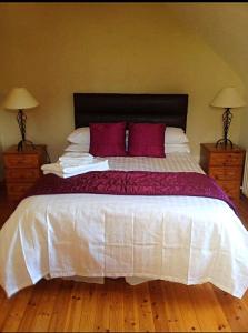 a bedroom with a large white bed with red pillows at Earlscourt in Glenbeigh
