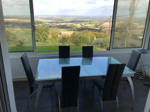 uma sala de jantar com mesa, cadeiras e janelas em Maison entre terre et mer em Gouézec