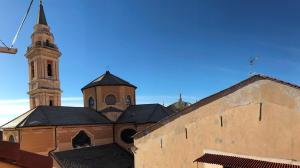 インペリアにあるMansarda Amendolaの時計塔と建物のある教会