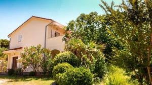 a house with trees and bushes in front of it at Adria Arba Apartments in Rab