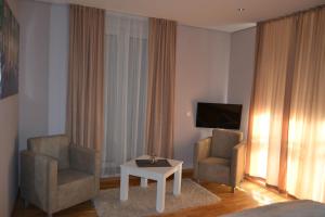 een hotelkamer met 2 stoelen, een tafel en een televisie bij B&B Alex18 in Niš