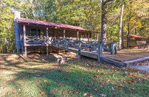 a log cabin in the woods with a wooden porch at Lake Barkley State Resort Park in Cadiz