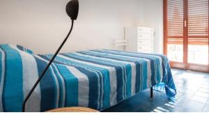 een slaapkamer met een bed met een blauw en wit gestreepte deken bij Villa Betty in Porto Clementino