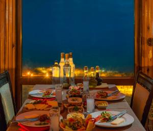 einen Tisch mit Teller mit Lebensmitteln und Flaschen Wein in der Unterkunft Assos Kartal Yuvasi Hotel in Sazlı