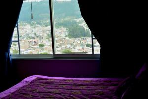 a bedroom with a view of a city from a window at Hostal Mirador de Otavalo in Otavalo