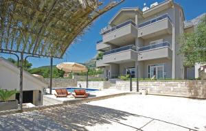 un grand bâtiment avec deux chaises et un parasol dans l'établissement Villa EM, à Makarska
