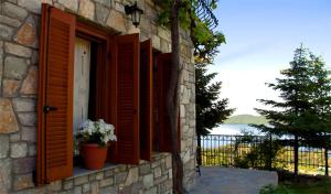 un edificio de piedra con una ventana con flores. en To Balkoni tis Limnis Plastira en Neochori