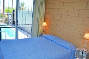 1 dormitorio con cama azul y balcón en Malaquias en Villa Carlos Paz