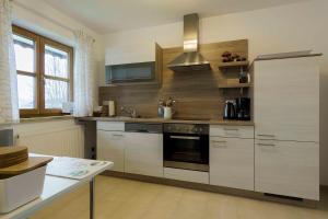 La cuisine est équipée de placards blancs et d'un four avec plaques de cuisson. dans l'établissement Ferienwohnung in Brand Finkenhöhe, à Brand