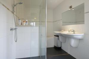uma casa de banho branca com um lavatório e um chuveiro em Johan's B&B met dakterras - since 2014 em Amsterdã