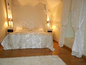 1 dormitorio con 1 cama blanca con 2 lámparas y 1 alfombra en Domaine de Puycarpin, en Belvès-de-Castillon