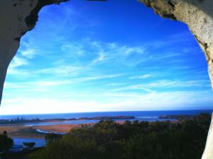 a view of the ocean through a hole in a rock at Al Oualidia Dar Diafa in Oualidia