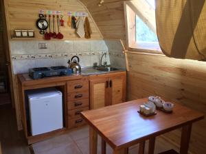 a small kitchen with a wooden table and a sink at Eco Cabañas Wanderlust in Puerto Puyuhuapi
