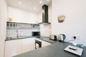 a kitchen with white cabinets and a counter top at Beautiful City Centre Apartment - Holyrood Park in Edinburgh +3 photos