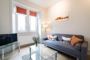 a living room with a couch and a tv at Beautiful City Centre Apartment - Holyrood Park in Edinburgh