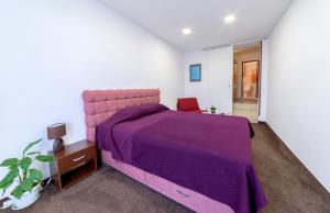 a bedroom with a purple bed and a chair at Hotel Stambolov in Veliko Tŭrnovo
