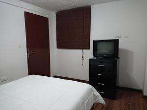 a bedroom with a bed and a tv on a dresser at Apartamentos Colonial Home in Quito
