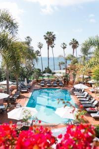 a large swimming pool with chairs and palm trees at La Valencia Hotel in San Diego